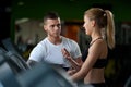 Personal coach talking with female client in gym