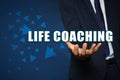 Personal development concept. Businessman holding virtual phrase Life Coaching on blue background, closeup Royalty Free Stock Photo