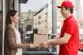 Personal home delivery. Courier gives parcels to girl, meets in front door
