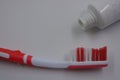 Personal hygiene products, a new plastic toothbrush with red and white bristles, with red rubber inserts and toothpaste Royalty Free Stock Photo
