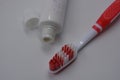 Personal hygiene products, a new plastic toothbrush with red and white bristles, with red rubber inserts and toothpaste Royalty Free Stock Photo