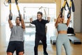 Personal instructor assists man and woman during fitness class in sports club.