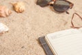 Personal planner and sunglasses on sandy beach closeup shot Royalty Free Stock Photo