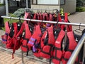 Personal red life vests in store. Many life jackets hang in a row on hangers. Protective safety clothing at rental boat store or Royalty Free Stock Photo