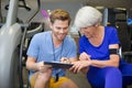 Personal trainer assist senior woman exercising on machine at gym Royalty Free Stock Photo