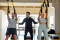 Personal trainer assists a couple that work out with elastic resistant strap. Royalty Free Stock Photo