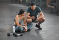 Personal trainer, coach or fitness instructor helping an active and fit woman in the gym. Young female athlete sitting Royalty Free Stock Photo