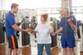 Personal trainer helping lift dumbbells to senior woman. Royalty Free Stock Photo