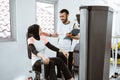 Personal trainer helping woman working with leg weight machine at the gym Royalty Free Stock Photo