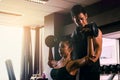 Personal trainer helping woman working lift heavy dumbbells two Royalty Free Stock Photo