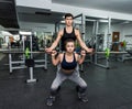 Personal trainer helping work with barbell in gym