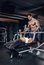 Personal trainer helping a young woman lift a barbell while working out in a gym Royalty Free Stock Photo