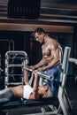 Personal trainer helping a young woman lift a barbell while working out in a gym Royalty Free Stock Photo