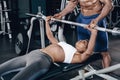 Personal trainer helping a young woman lift a barbell while working out in a gym Royalty Free Stock Photo