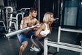 Personal trainer helping a young woman lift a barbell while working out in a gym Royalty Free Stock Photo