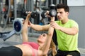 Personal trainer helping a young woman lift weights Royalty Free Stock Photo