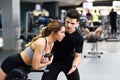 Personal trainer helping young woman lift weights