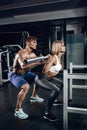 Personal trainer helping a young woman lift a barbell while working out in a gym Royalty Free Stock Photo