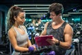 Personal trainer and his female client standing together and discussing nutrition or training plan on clipboard in gym Royalty Free Stock Photo