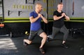 Personal trainer motivating senior man while leg lunges exercise