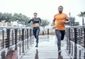 Personal trainer, rain and athletes running as exercise on a city bridge training, fitness or workout outdoors in town