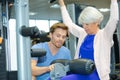 Personal trainer securing gym equipment around senior woman Royalty Free Stock Photo