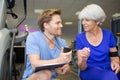 personal trainer showing stopwatch time to elderly woman