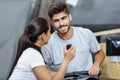 Personal trainer showing stopwatch time to man using rowing machine