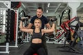 personal trainer with slim woman client doing bicep curls working out in gym Royalty Free Stock Photo