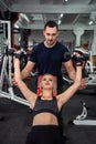 personal trainer with slim woman client doing bicep curls working out in gym Royalty Free Stock Photo
