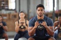 Personal trainer squatting with a team of athletes in a workout session at a fitness club. Portrait of a fit, active and