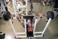 Personal trainer with a tattooed body does the workout in the gym using a flat bench with barbell support.