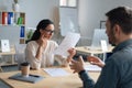 Personnel manager communicating with vacancy candidate, reading resume during job interview at office