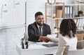 Personnel manager and young job applicant shaking hands at modern company office