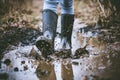 persons feet in rubber boots splashing in a muddy puddle Royalty Free Stock Photo