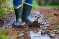 persons feet in rubber boots splashing in a muddy puddle Royalty Free Stock Photo