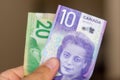 Persons hand giving the Currency of the Canada - One purple ten dollar and green twenty notes with Viola Desmond spread out on a Royalty Free Stock Photo