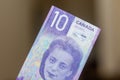 Persons hand giving the Currency of the Canada - One purple ten dollar notes with Viola Desmond spread out on a brown background. Royalty Free Stock Photo