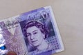 Persons hand giving the Currency of the England in the United Kingdom - One purple twenty pound note spread out on a white