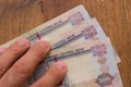 Persons hand giving the Currency of the United Arab Emirates UAE on table - Five hundred Dirham notes spread out on a brown Royalty Free Stock Photo