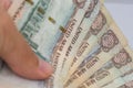 Persons hand giving the Currency of the United Arab Emirates UAE - Thousand Dirham notes spread out on a white background. Money