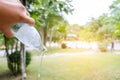 Persons hand holding a bottle of water poring it out in garden, Royalty Free Stock Photo