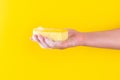 Persons hand holding yellow sponge for dish wash. Washcloth covered in soap. Domestic chores and supplies concept. Sensitive