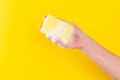 Persons hand holding yellow sponge for dish wash. Washcloth covered in soap. Domestic chores and supplies concept. Sensitive