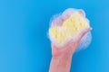 Persons hand holding yellow sponge for dish wash. Washcloth covered in soap. Domestic chores and supplies concept. Sensitive