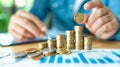 A persons hand places a single coin atop a growing stack of coins, symbolizing saving money Royalty Free Stock Photo