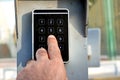 a persons hand pressing a password on a numerical keypad to lock or unlock an alarm system, opening garage gate for car entry, Royalty Free Stock Photo