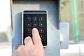 a persons hand pressing a password on a numerical keypad to lock or unlock an alarm system, opening garage gate for car entry, Royalty Free Stock Photo