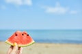 Hand Holding a Slice of Watermelon on a Sunny Beach Day Royalty Free Stock Photo