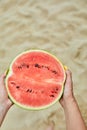 Hand Holding a Slice of Watermelon on a Sunny Beach Day Royalty Free Stock Photo